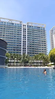 a person in a swimming pool in front of a large building at Condo Azure Urban Resort Paranaque in Manila