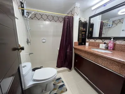a bathroom with a toilet and a sink and a mirror at Spacious 3BR with Huge TV near BGC Makati Airport in Manila