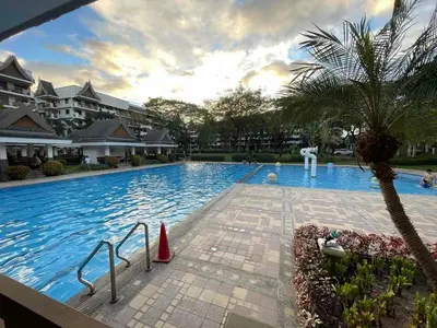 a large swimming pool with a palm tree and buildings at Spacious 3BR with Huge TV near BGC Makati Airport in Manila