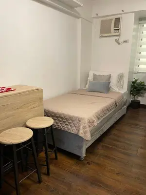a small bedroom with a bed and two stools at Spacious 3BR with Huge TV near BGC Makati Airport in Manila