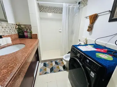 a washing machine in a bathroom with a sink at Spacious 3BR with Huge TV near BGC Makati Airport in Manila