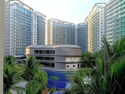 a building with palm trees in front of tall buildings at Azure Urban Resort paranaque in Manila