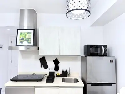 a kitchen with white cabinets and a refrigerator at Lé Boom's Staycation in Manila