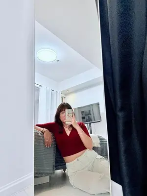 a woman sitting on a couch in front of a mirror at Lé Boom's Staycation in Manila