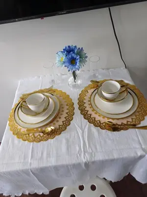 a white table with two plates and a vase with flowers at Cozy Suites in Air residence in Manila