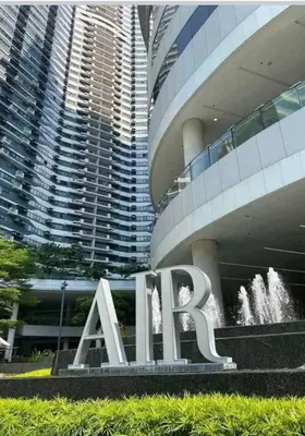 a large sign in front of a building with a fountain at Cozy Suites in Air residence in Manila