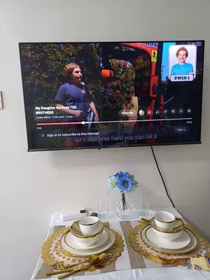a table with two plates and a tv on the wall at Cozy Suites in Air residence in Manila