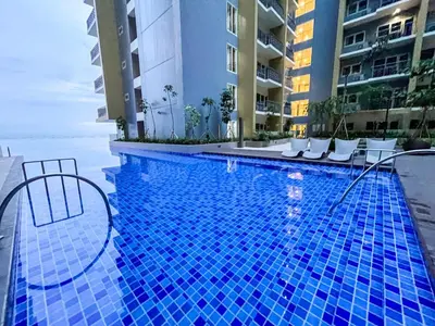 a large blue swimming pool with chairs and buildings at Luxurious 3BR near Solaire & Okada w Infinity Pool in Manila