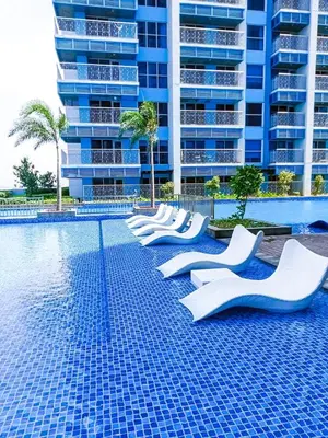 a swimming pool with white chairs in front of a tall building at Luxurious 2BR near Solaire, Okada, Airport in Manila