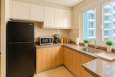 a kitchen with a black refrigerator and a sink at Luxurious 2BR near Solaire, Okada, Airport in Manila