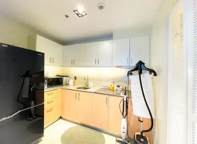 a kitchen with white cabinets and a black refrigerator at Lovely & Luxury 1BR near Solaire, Okada w Sunset in Manila