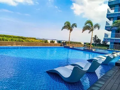 a swimming pool with blue water and palm trees at Spacious & Luxury 1BR near Solaire, Okada, Airport in Manila
