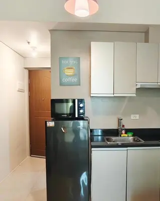 a kitchen with a black refrigerator and a sign on the wall at The Beacon Makati by Christine Suites PH near Greenbelt Mall in Manila