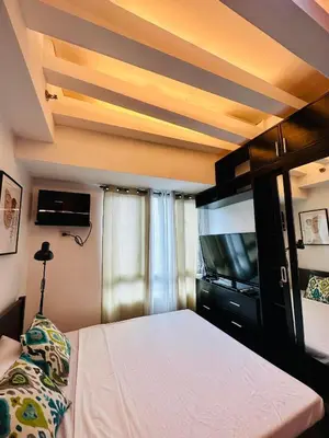 a bedroom with a bed and a flat screen tv at The Beacon Makati by Christine Suites PH near Greenbelt Mall in Manila