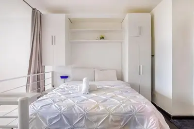 a white bedroom with a large white bed in it at 1 Bedroom Loft in Gramercy Residences Makati in Manila