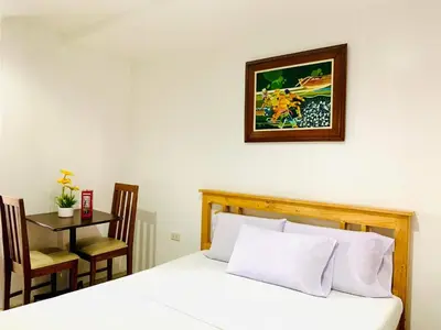 a bedroom with a bed with a table and a picture on the wall at The Seaside Residences in Manila