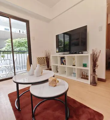 a living room with two tables and a tv at Forbes Town in Manila