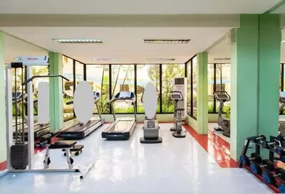 a gym with treadmills and elliptical machines and windows at Forbes Town in Manila