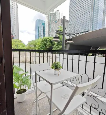 a white table and chairs on a balcony with buildings at Forbes Town in Manila