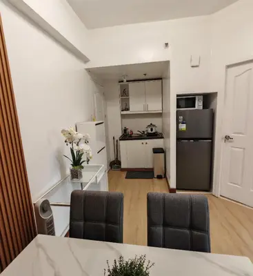 a kitchen with a black refrigerator and a table at Forbes Town in Manila