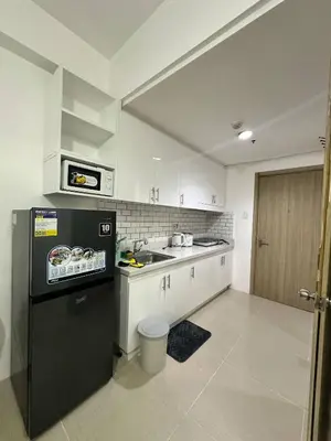 a kitchen with a black refrigerator and a sink at Shore Residences Mall of Asia in Manila