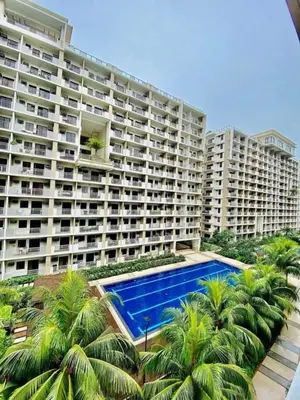 a large apartment building with a swimming pool and palm trees at 2BR FREE PARKING Calathea Place in Manila