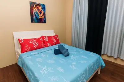 a bed with a blue comforter and red pillows at Metro mood haven Makati relax recharge repeat 1765 in Manila