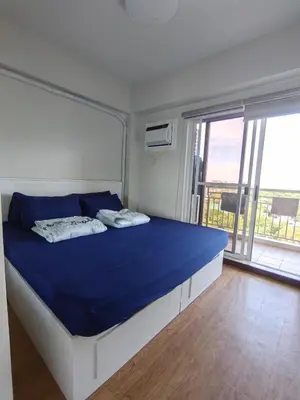 a bedroom with a bed with blue sheets and a large window at The Atherton by DMCI- 2BR FREE PARKING in Manila