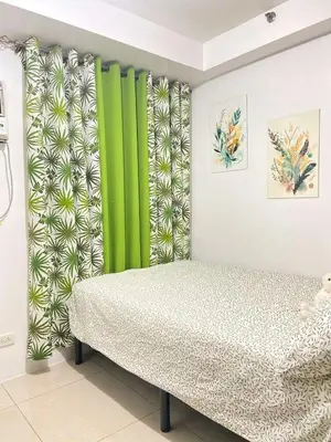 a bedroom with green and white curtains and a bed at Leisure Suite Staycation in Manila