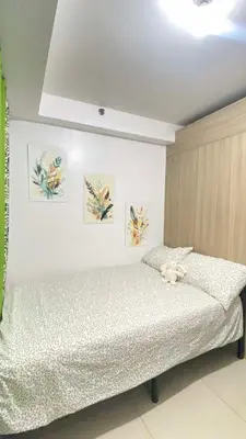 a bed in a bedroom with paintings on the wall at Leisure Suite Staycation in Manila