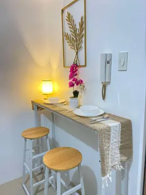 a counter with two stools and a table with flowers at Leisure Suite Staycation in Manila