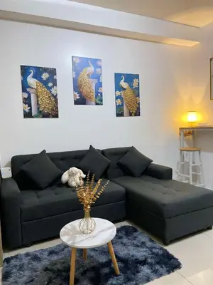 a living room with a black couch and a table at Leisure Suite Staycation in Manila