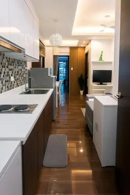a kitchen with white counters and a living room at The Comfy Cove Swim Stream in Central Makati 2272 in Manila