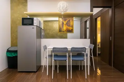 a kitchen with a table with chairs and a refrigerator at The Comfy Cove Swim Stream in Central Makati 2272 in Manila