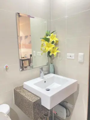 a bathroom with a sink and a vase of yellow flowers at M&N Condotel in Manila