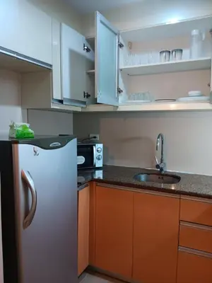 a kitchen with a white refrigerator and a sink at M&N Condotel in Manila