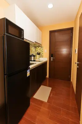 a kitchen with a black refrigerator and a door at Sunlit Makati Haven Cozy 1BR Gym Pool 1703 in Manila