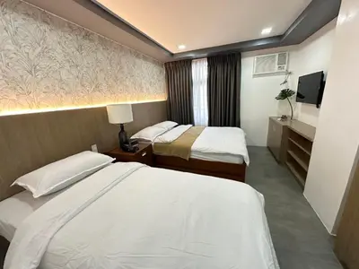 a hotel room with two beds and a television at Gimaca Boutique Hotel in Manila
