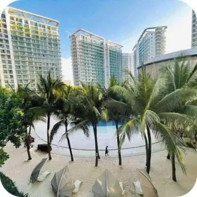 a beach with palm trees in front of buildings at Azure Urban Resort paranaque in Manila