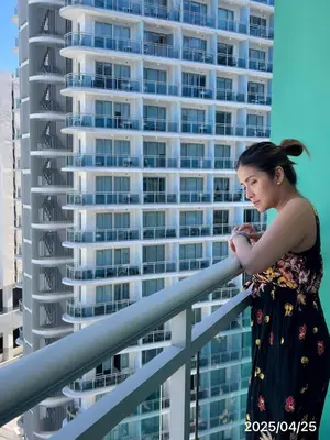 a woman standing on a railing in front of a tall building at Azure Urban Resort paranaque in Manila