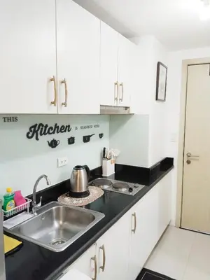 a kitchen with white cabinets and a sink at Maria's staycation in Manila
