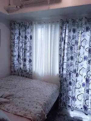 a bedroom with a bed and a window with curtains at Maria's staycation in Manila