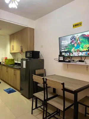a kitchen with a table and a television on the wall at Apartments at Shore 1 Residences MOA Pasay Near Airport in Manila