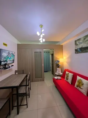 a living room with a red couch and a table at Apartments at Shore 1 Residences MOA Pasay Near Airport in Manila