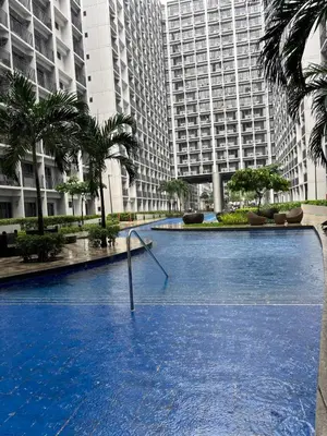 a large swimming pool in a city with tall buildings at Cozy Condo Near MOA & Airport in Manila