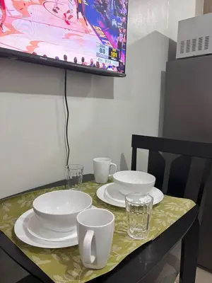 a table with white plates and glasses on it at Cozy Condo Near MOA & Airport in Manila