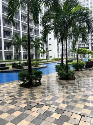 a resort courtyard with palm trees and a pool at Cozy Condo Near MOA & Airport in Manila