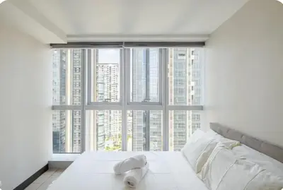 a bedroom with a white bed with a large window at Mystay25V-ParksuitesTower1 in Manila