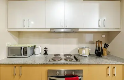 a kitchen with white cabinets and a stove and a microwave at Mystay25V-ParksuitesTower1 in Manila