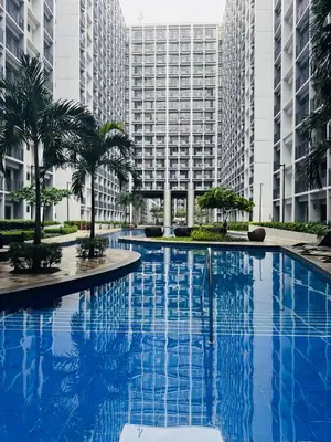 a large swimming pool with palm trees and buildings at MOA Newly Turn Over 1 bedroom with balcony PRIER Place in Manila